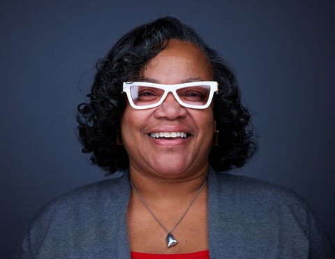 Photo portrait of Tonia Brinston, in her signature white glasses and smiling